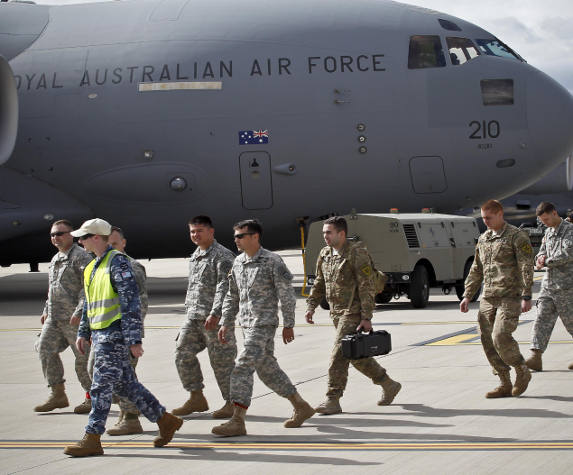 RAAF members walking with an airplane behind.